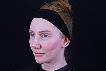 Woman with headband against black background.