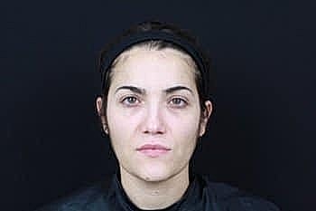 Woman with natural makeup against a black background.