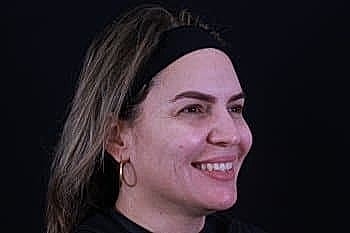 Smiling woman with medium-length hair, black background.