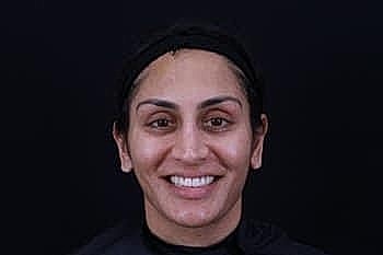 Smiling woman with dark hair on black background