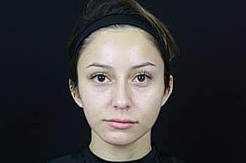 Woman with natural makeup against black background.