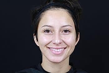 Smiling person with short hair against dark background