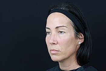 Woman with a headband against a dark background.