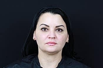 Woman with dark hair against a black background.