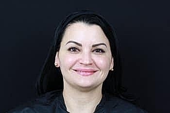 Smiling woman against a black background.