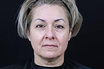 Middle-aged woman with casual hairstyle against black background.