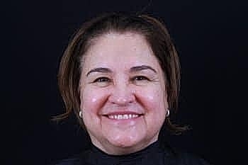 Smiling woman with shoulder-length hair against dark background