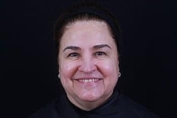 Smiling woman with dark background.