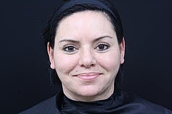Smiling woman with dark hair and neutral background.