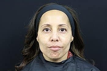 Woman with long hair and neutral expression.