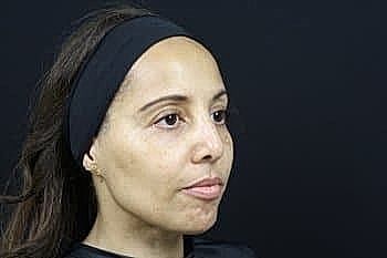 Woman with headband against black background.