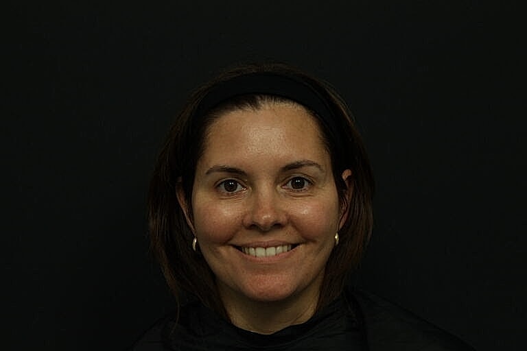 Smiling woman with medium-length hair against black background.