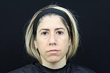 Woman with short hair, neutral expression, black background.