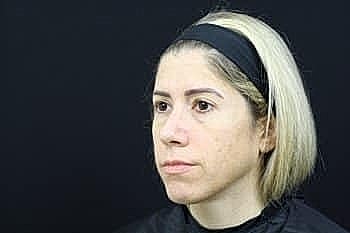 Woman with short blonde hair against black background.