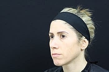 Woman with headband against black background.
