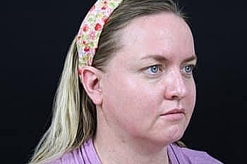 Woman with hairband, serious expression, neutral background.