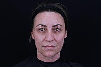 Person with neutral expression against dark background.