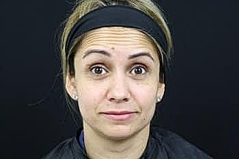 Person with neutral expression against dark background.