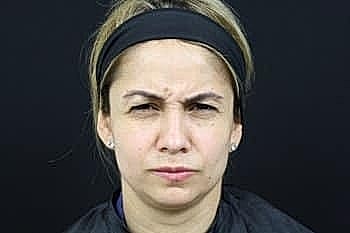 Woman with serious expression against black background.