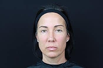 Neutral expression on woman against black background.