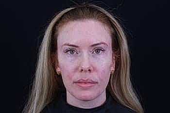 Woman with long hair against black background.