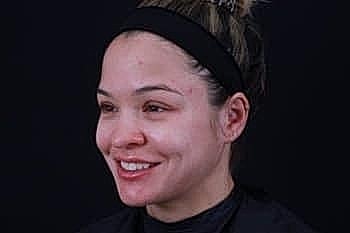 Smiling person with natural makeup on dark background.