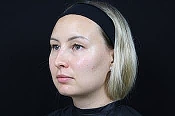 Woman with short blonde hair against black background.