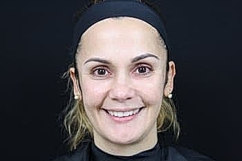 Smiling woman with a headband against dark background.