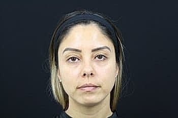 Woman with straight hair against a dark background.