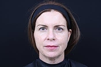 Woman facing forward against dark background.