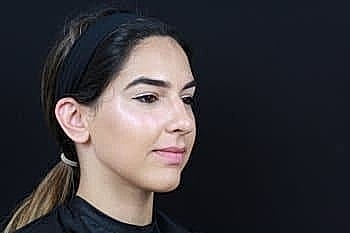 Woman with sleek hairstyle against black background.