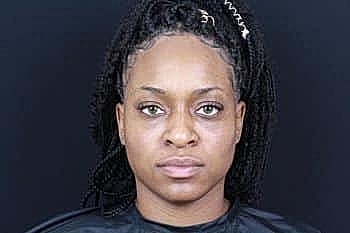 Person with braided hair against a dark background.