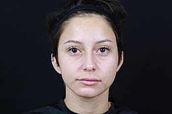 Person with short dark hair against black background.