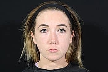 Young woman with long hair against black background.