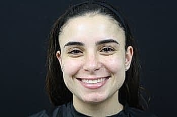 Smiling woman against a black background.