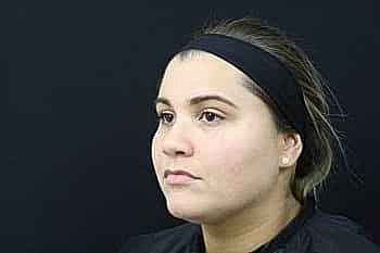 Young woman with headband against black background.