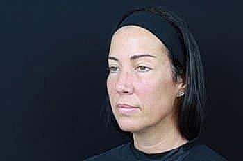 Woman with black headband and neutral expression.