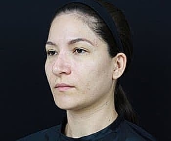 Woman with neutral expression against dark background.