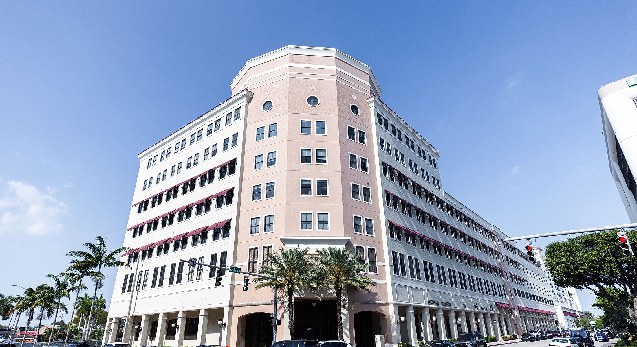 Modern building with palm trees under blue sky.