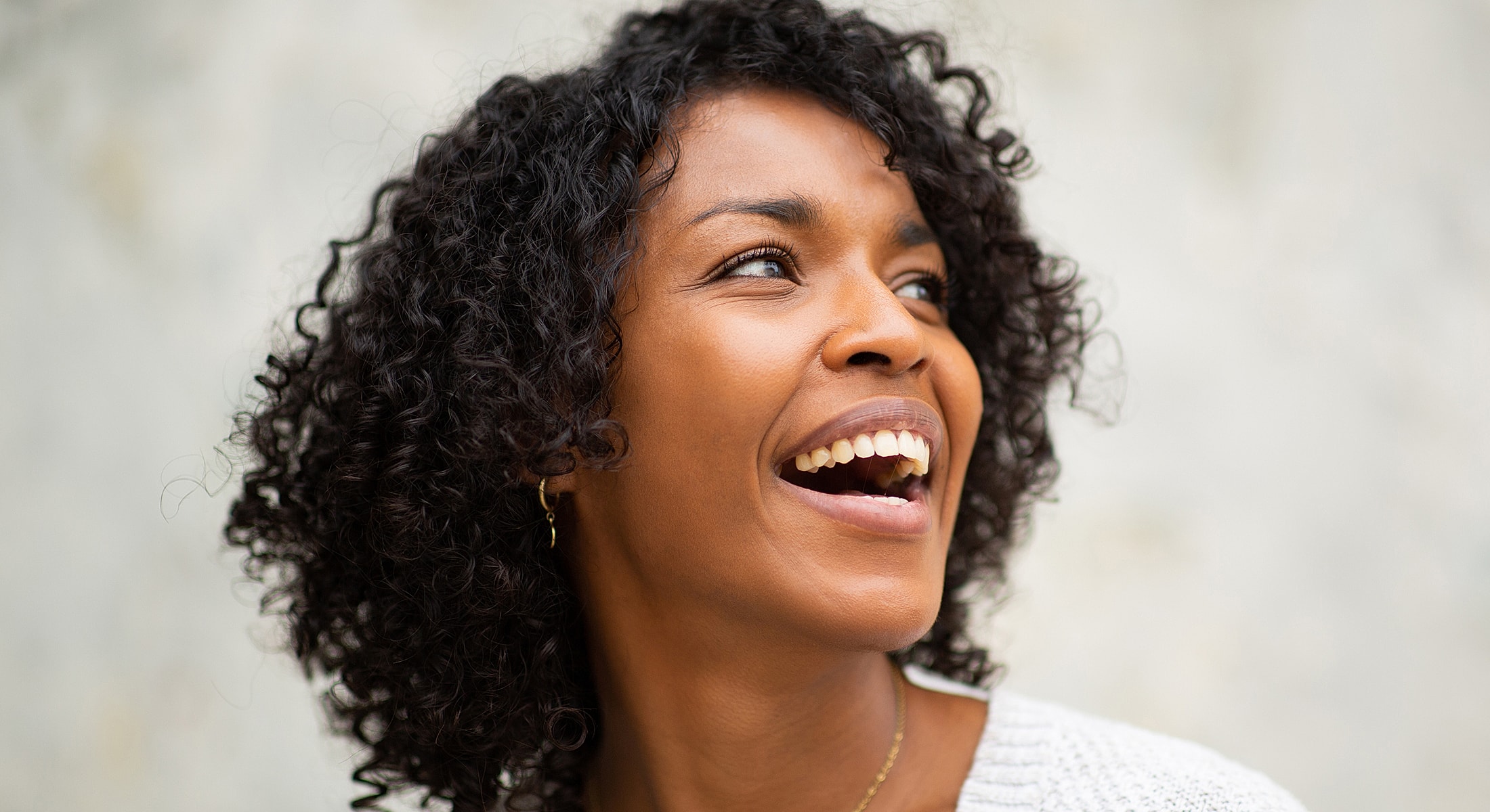 Smiling woman with curly hair on neutral background