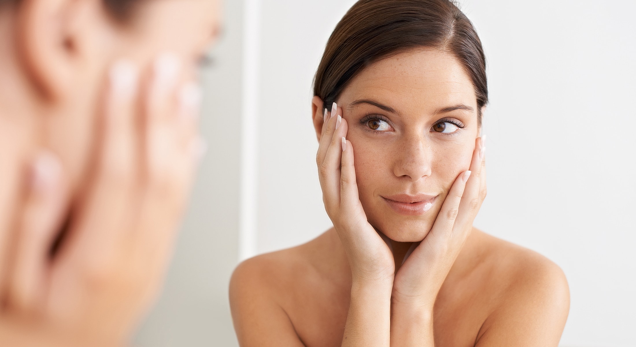 Woman gazing at her reflection, skincare routine.