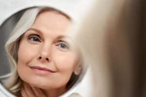 Mature woman looking at her face in a mirror